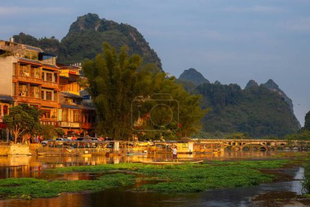 Téléchargez les photos : Un beau cliché du village asiatique du Guangxi avec des bâtiments entourés d'une rivière et de collines - en image libre de droit