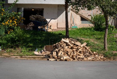 Téléchargez les photos : Une pile de coupes de bois recueillies par un côté de la rue, se préparant pour le chauffage hivernal - en image libre de droit