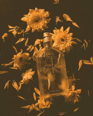 Foto de Un plano vertical del perfume Calvin Klein One con decoraciones florales e iluminación tenue - Imagen libre de derechos