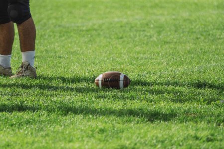 Photo for An American football player with a ball on the green field. - Royalty Free Image