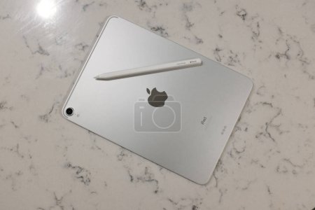 Foto de La parte posterior de un iPad de plata pro 10 "con lápiz de manzana blanca 2 en una encimera de mármol blanco. - Imagen libre de derechos
