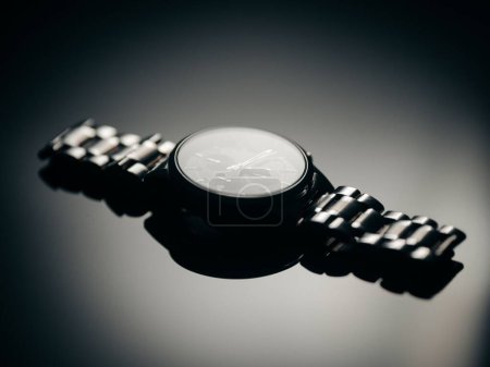 Téléchargez les photos : Un gros plan d'une montre de luxe en métal et son reflet sur un fond isolé - en image libre de droit