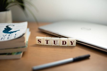 Téléchargez les photos : L'étude d'orthographe des carreaux de scrabble sur un bureau en bois avec un ordinateur portable, un stylo et des livres. - en image libre de droit