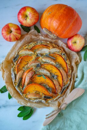 Photo for A homemade pumpkin quiche on the table with a pumpkin and apples - Royalty Free Image