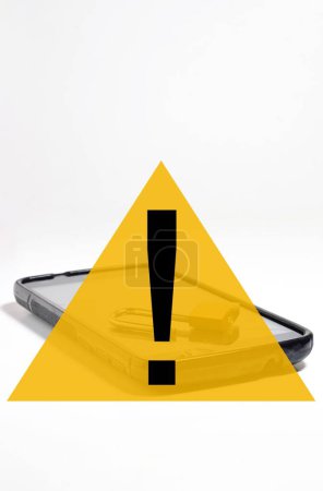 Foto de Un concepto de seguridad cibernética con señal de advertencia triangular amarilla y teléfono móvil en segundo plano - Imagen libre de derechos