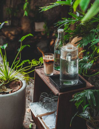 Téléchargez les photos : Un plan vertical d'une table basse en bois avec des cruches d'eau et un latte glacé dans un café - en image libre de droit
