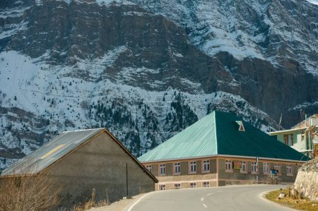 Téléchargez les photos : Vue panoramique d'hiver depuis la route asphaltée dans les montagnes couvertes de neige et d'arbres sur le côté de la route sur un fond de ciel bleu et de nuages - en image libre de droit