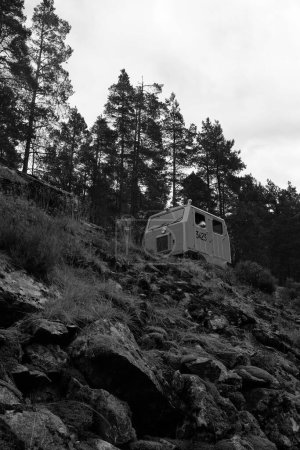 Téléchargez les photos : Plan vertical à faible angle d'une automobile abandonnée sur la roche en niveaux de gris - en image libre de droit