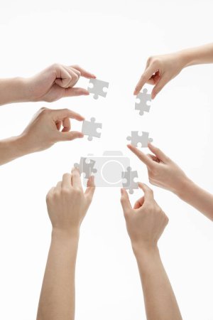 Téléchargez les photos : Un plan vertical des mains tenant des pièces de puzzle devant un fond blanc - en image libre de droit