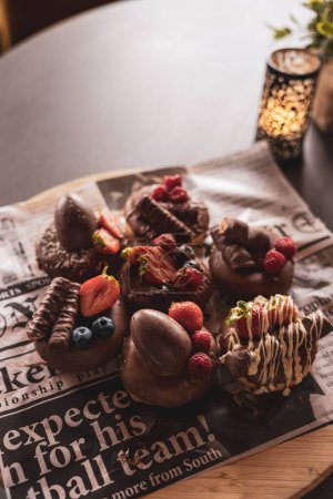 Foto de Un hermoso chupito de deliciosas rosquillas de chocolate decoradas con bayas - Imagen libre de derechos