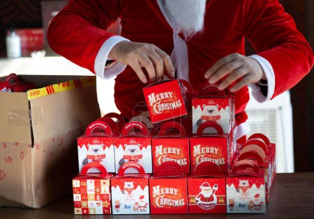 Foto de Un Papá Noel arreglando cajas de regalo de Navidad en una mesa - Imagen libre de derechos