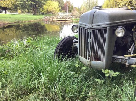 Téléchargez les photos : Un tracteur à côté d'un magnifique étang - en image libre de droit