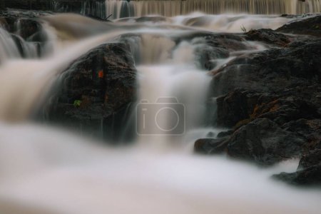 Téléchargez les photos : Un long plan d'exposition d'une cascade qui descend dans les gros rochers pendant la journée - en image libre de droit