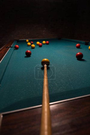 Photo for A vertical footage of a billiard table with balls and cue in a dark room - Royalty Free Image
