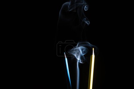 Téléchargez les photos : Un gros plan de crayons colorés et de fumée blanche sur fond noir - en image libre de droit