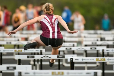 Foto de Una vista panorámica de una atleta femenina compitiendo en el evento de obstáculos en una pista de secundaria - Imagen libre de derechos