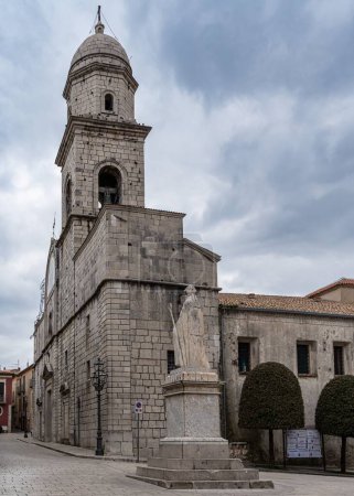 Foto de La catedral de Nusco con un campanario de cúpula redonda se cierne sobre una estatua de un santo en Campania, Italia - Imagen libre de derechos