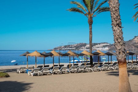Foto de Las sillas plegables y sombrillas ante el paisaje marino en la playa de Almuñecar en un día soleado - Imagen libre de derechos