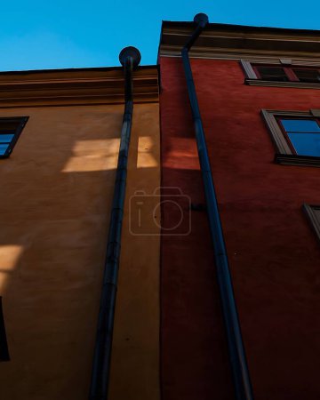 Photo for A low angle shot of buildings with rainwater drainage pipes under blue sky in Gamla Stan, Stockholm - Royalty Free Image