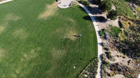 Téléchargez les photos : Une vue aérienne de la personne debout sur une pelouse verte luxuriante propre dans le parc - en image libre de droit