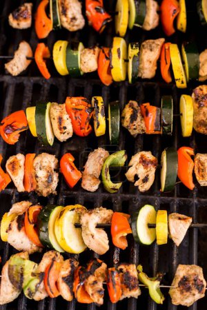 Foto de Una toma vertical de brochetas de verduras y pollo en una parrilla - Imagen libre de derechos