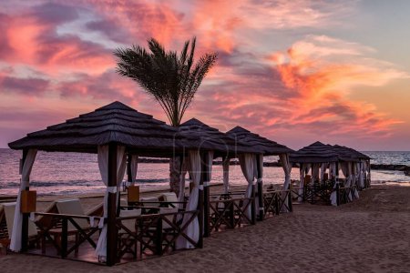 Téléchargez les photos : Les alcôves romantiques sur la plage de sable fin à Chypre au coucher du soleil - en image libre de droit