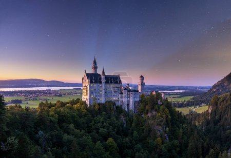 Photo for The Neuschwanstein Castle in the middle of trees and lakes under the starry sky in Bavaria, Germany - Royalty Free Image