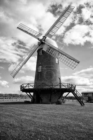 Téléchargez les photos : Un plan en niveaux de gris d'un moulin à vent contre le ciel nuageux - en image libre de droit