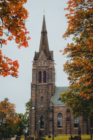 Foto de El exterior de la iglesia de Vallsjo kyrka en Suecia con árboles de otoño, plano vertical - Imagen libre de derechos