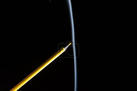 Photo for A closeup of yellow colored pencil touching the white smoke coming from below, with copy space. - Royalty Free Image