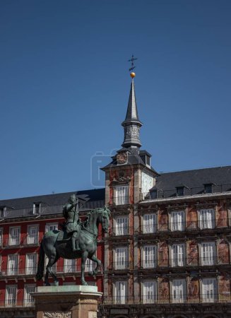 Photo for A vertical shot of a statue in Plaza Mayor public space and a tower with a cross on the top - Royalty Free Image
