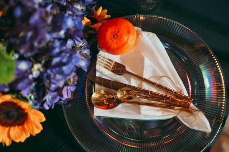 Téléchargez les photos : Une vue de dessus d'une table luxueuse avec une mandarine sur une assiette entourée de décorations florales, préparatifs pour une célébration - en image libre de droit