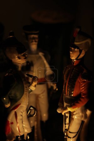Téléchargez les photos : Trois figurines en porcelaine de soldat de l'époque napoléonienne debout comme si elles étaient éclairées par un feu de camp - en image libre de droit