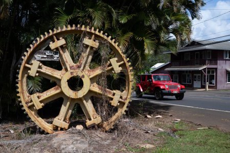 Téléchargez les photos : Une roue de broyage de canne à sucre à Kauai, Hawaï, maintenant une décoration dans le parking d'un magasin de courtepointe - en image libre de droit