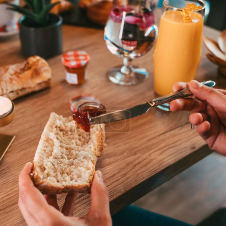 Foto de Una toma de manos de alto ángulo haciendo un sándwich de mermelada junto a la mesa de madera - Imagen libre de derechos