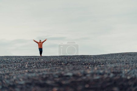 Foto de Un joven parado en el borde de un acantilado con un cielo nublado en el fondo - Imagen libre de derechos
