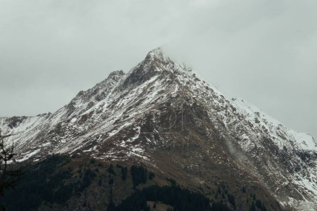 Foto de Un paisaje de una montaña cubierta de nieve bajo un cielo gris nublado en invierno - Imagen libre de derechos
