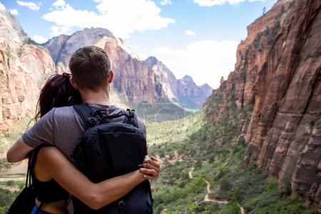 Photo for A young couple hugging looking over Zion national park canyon  with a cloudy blue sky in the background, United States - Royalty Free Image