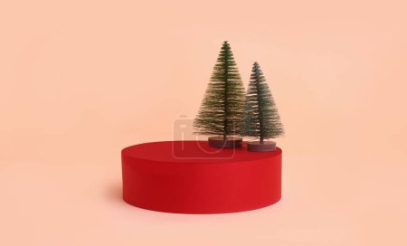 Foto de Linda configuración de Navidad con pequeños árboles de Navidad en el podio rojo para la exhibición del producto contra la pared del melocotón - Imagen libre de derechos