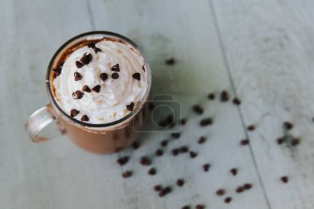Téléchargez les photos : Une vue de dessus d'un verre de chocolat chaud sur une table, avec de la crème sur le dessus et des morceaux de chocolat sur le côté - en image libre de droit