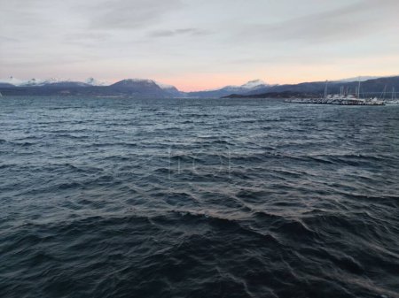 Téléchargez les photos : Une vue panoramique sur les vagues de la mer par une journée venteuse avec des montagnes et un port en arrière-plan - en image libre de droit