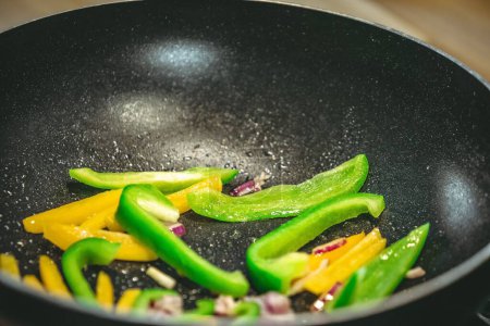 Photo for A closeup shot of a pan with sliced bell peppers being cooked - Royalty Free Image