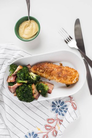 Photo for A vertical top view of shot of the chicken with broccoli and meat on a bowl with a fork and knife - Royalty Free Image