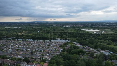 Photo for A bird's-eye view of a suburban area with the background of woodland and farmland under a cloudy sky - Royalty Free Image