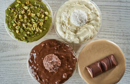 Téléchargez les photos : Une vue de dessus des puddings dans quatre tasses recouvertes de crèmes ayant des goûts différents - en image libre de droit