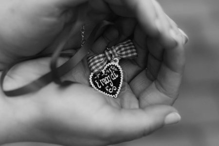 Foto de Un primer plano en escala de grises de un colgante en forma de corazón en una mano - Imagen libre de derechos