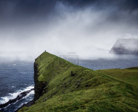 Téléchargez les photos : Une vue paysage des formations rocheuses près de la plage par une journée nuageuse et brumeuse - en image libre de droit