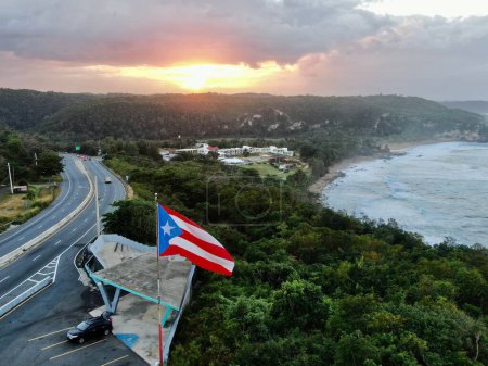 Photo for An aerial shot of the Flag of Puerto Rico waving in the air at a golden sunset in Quebradillas - Royalty Free Image