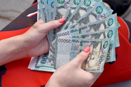 Foto de Una vista superior de las manos femeninas en vestido rojo sosteniendo y contando muchos billetes armenios de 20000 dram - Imagen libre de derechos