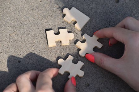 Téléchargez les photos : Une vue de dessus des mains féminines reliant des pièces de puzzle, ombre sur le sol - en image libre de droit
